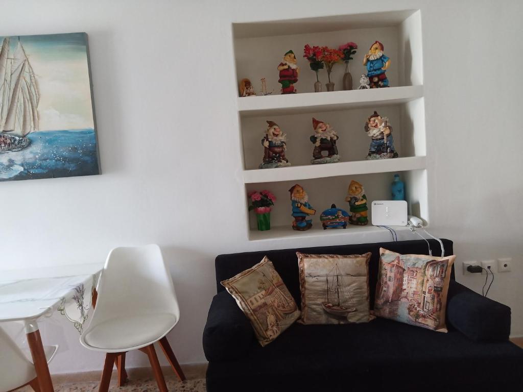 uma sala de estar com um sofá preto e prateleiras em ARGYRO'S HOUSE em Kimolos