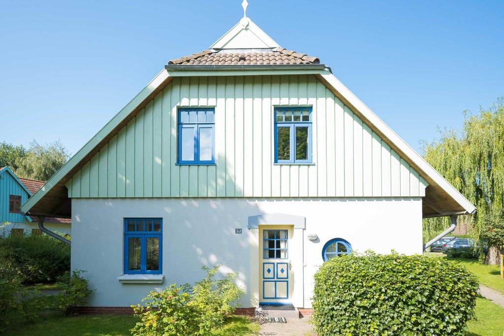 une maison blanche avec un toit en gambrel dans l'établissement Ferienhaussiedlung Strandperlen Sanddornhof 5d (Typ IV), à Wustrow