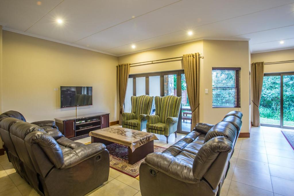 a living room with leather couches and a tv at Zimbali Holiday Home - 3 Baluwatu in Durban