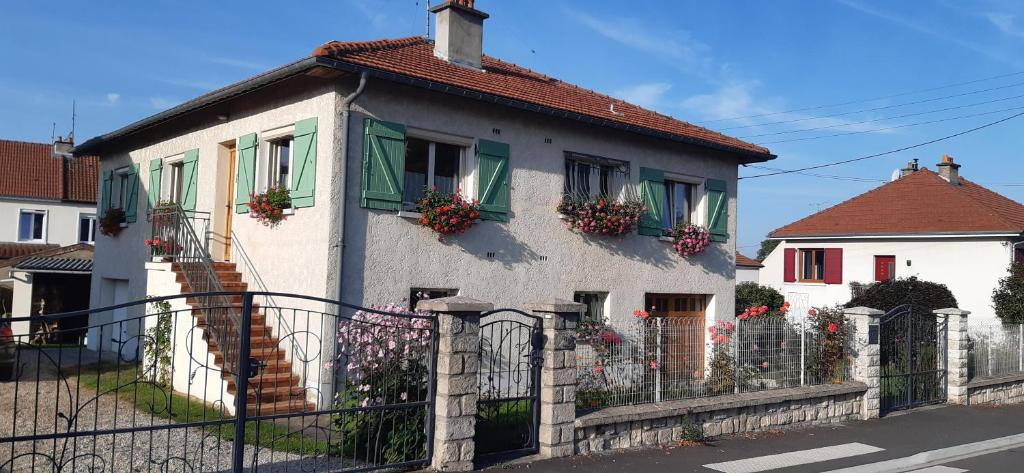 una casa blanca con flores en las ventanas en Chez Evelyne chambre d'hôtes chez l'habitant, en Verdún