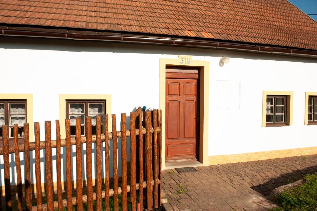 ein weißes Haus mit einer Holztür und einem Zaun in der Unterkunft Chalupa Barborka in Mezimesti