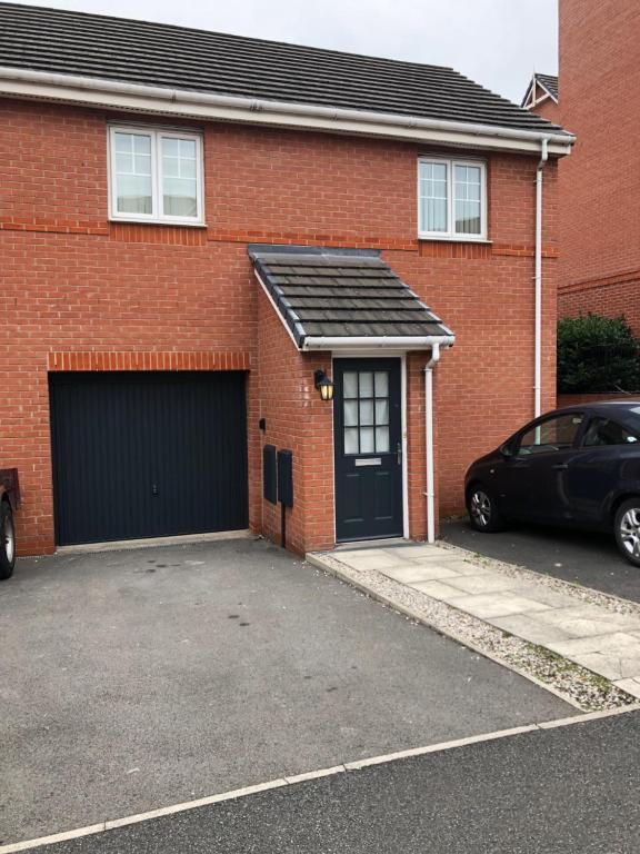 a red brick house with a garage and a car at Modern stylish flat over garage in Crewe