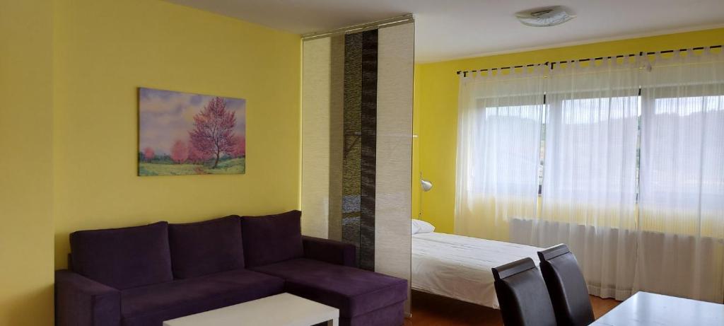 a living room with a purple couch and a bedroom at Studio apartman Sandra in Začretje