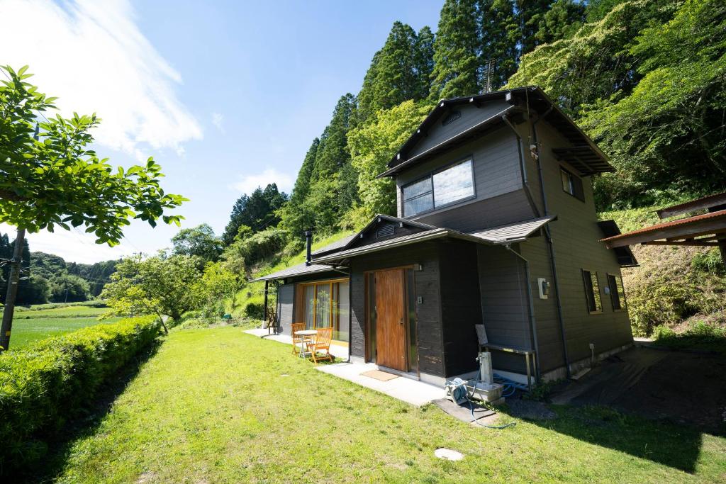 una pequeña casa en un campo con un patio de césped en Isumi Enokisawa -いすみ 四季の家 榎澤- ペット可 en Isumi