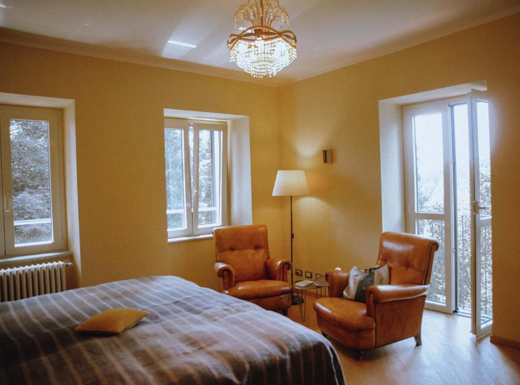sypialnia z 2 krzesłami, łóżkiem i żyrandolem w obiekcie La Foresteria di Villa Piazzo w mieście Pettinengo