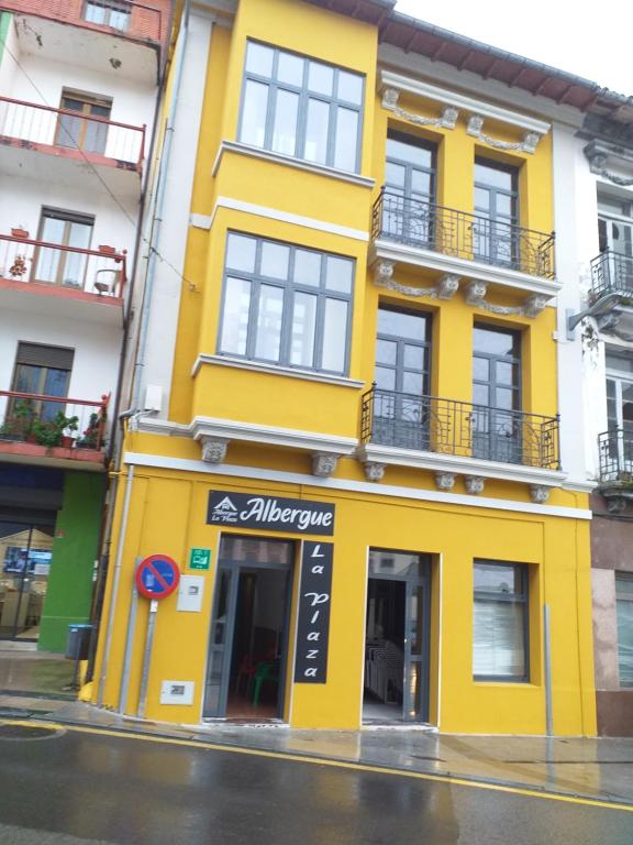 um edifício amarelo no lado de uma rua em Albergue La Plaza em Tineo