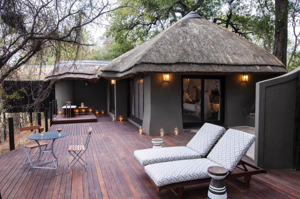 a large deck with chairs and a thatch roof at Jock Safari Lodge in Skukuza