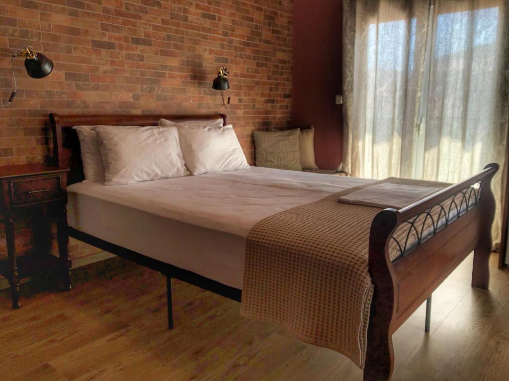 - un grand lit dans une chambre dotée d'un mur en briques dans l'établissement Guesthouse Monopati - Ξενώνας Μονοπάτι, à Lechovo