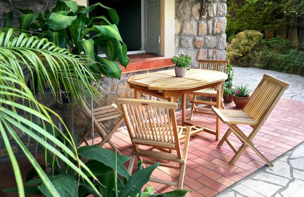 une table et des chaises en bois sur une terrasse dans l'établissement VILLA ARVOR CANNES Appartement indépendant en bas de maison, à Cannes