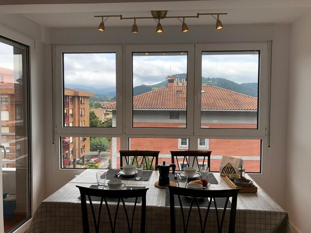 una sala da pranzo con tavolo e una grande finestra di Piso céntrico y tranquilo en Gernika a Guernica y Luno