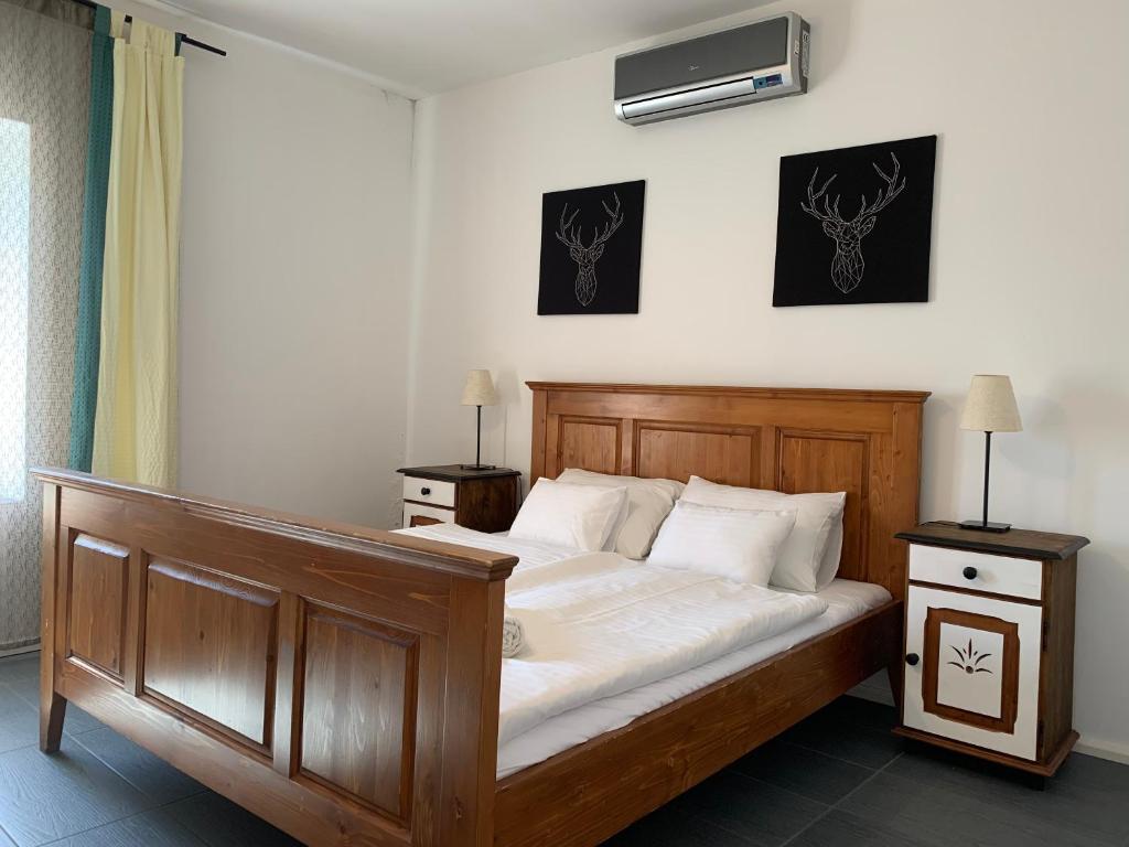 1 dormitorio con cama de madera con sábanas blancas en MiLLER's Inn Panzió és Étterem, en Nagyoroszi
