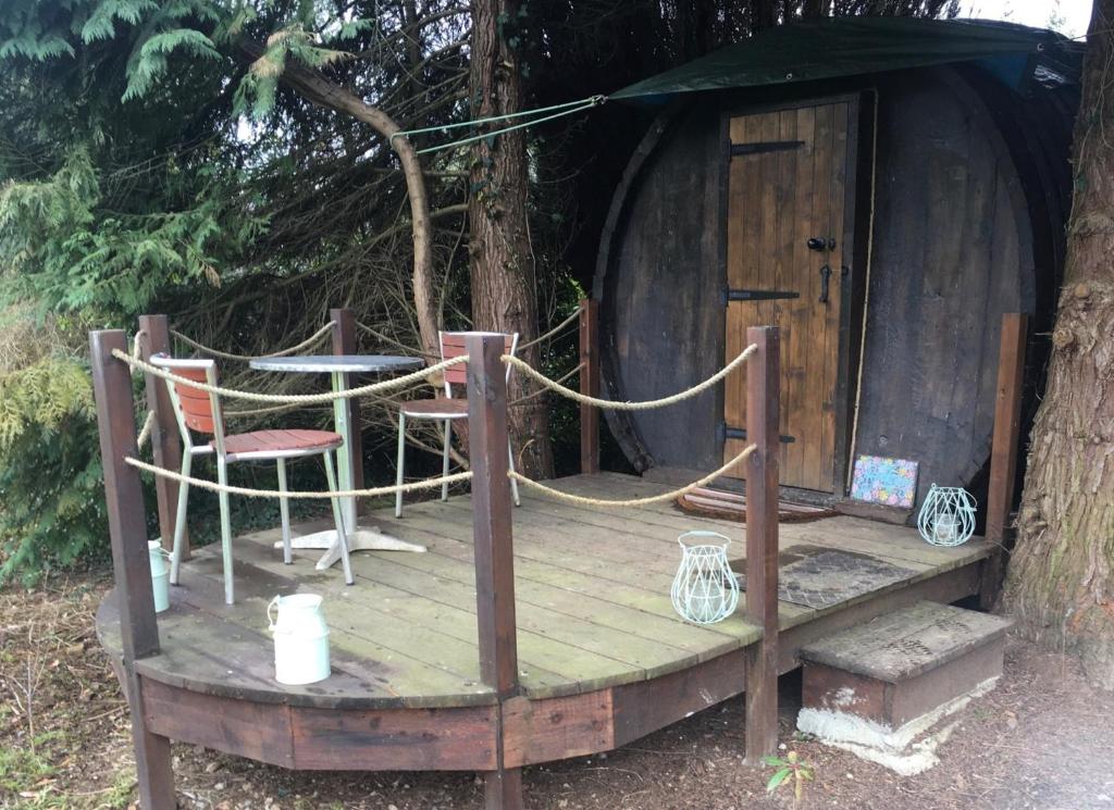 een houten terras met een stoel en een boomhut bij Beautiful unique Barrel in lakeview tranquility in Perrou
