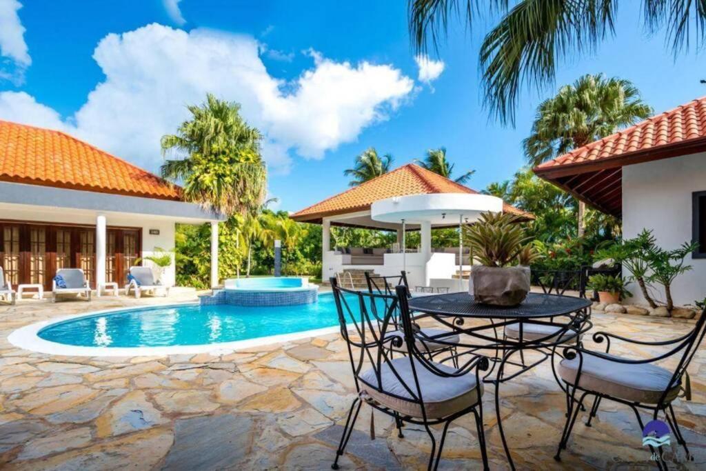 a patio with a table and chairs next to a swimming pool at Luxury Villa Casa De Campo in La Romana