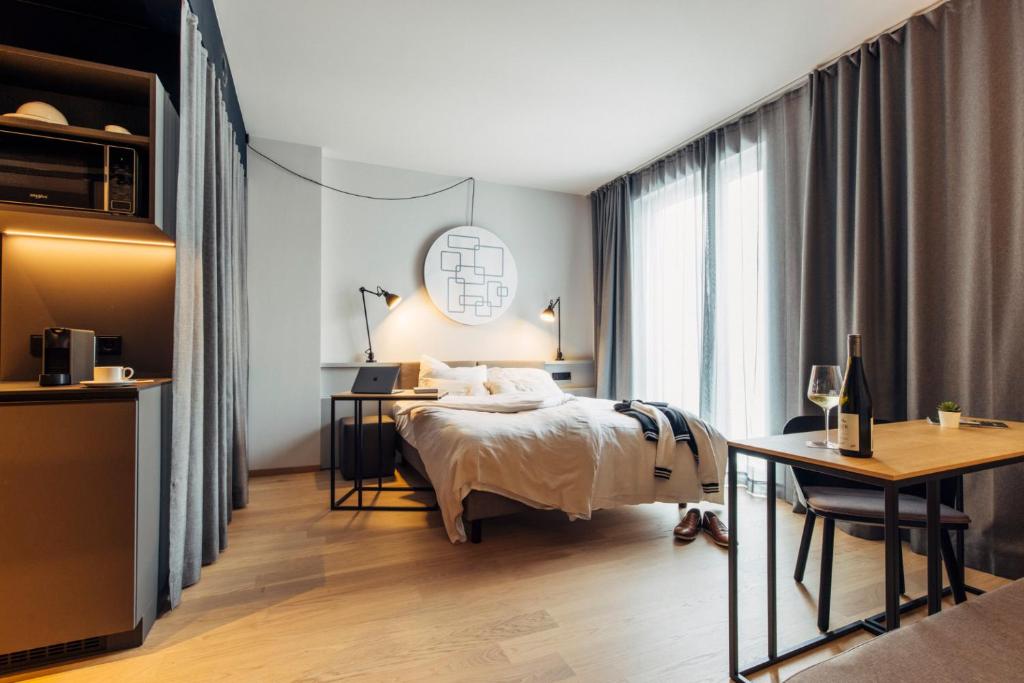 a bedroom with a bed and a desk and a window at harry's home hotel & apartments in Bischofshofen