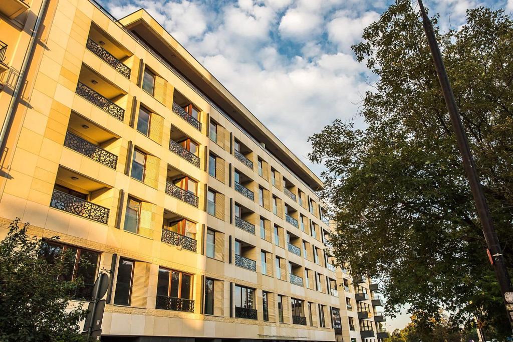 a large yellow building with a tree in front of it at P&O Serviced Apartments Solec in Warsaw