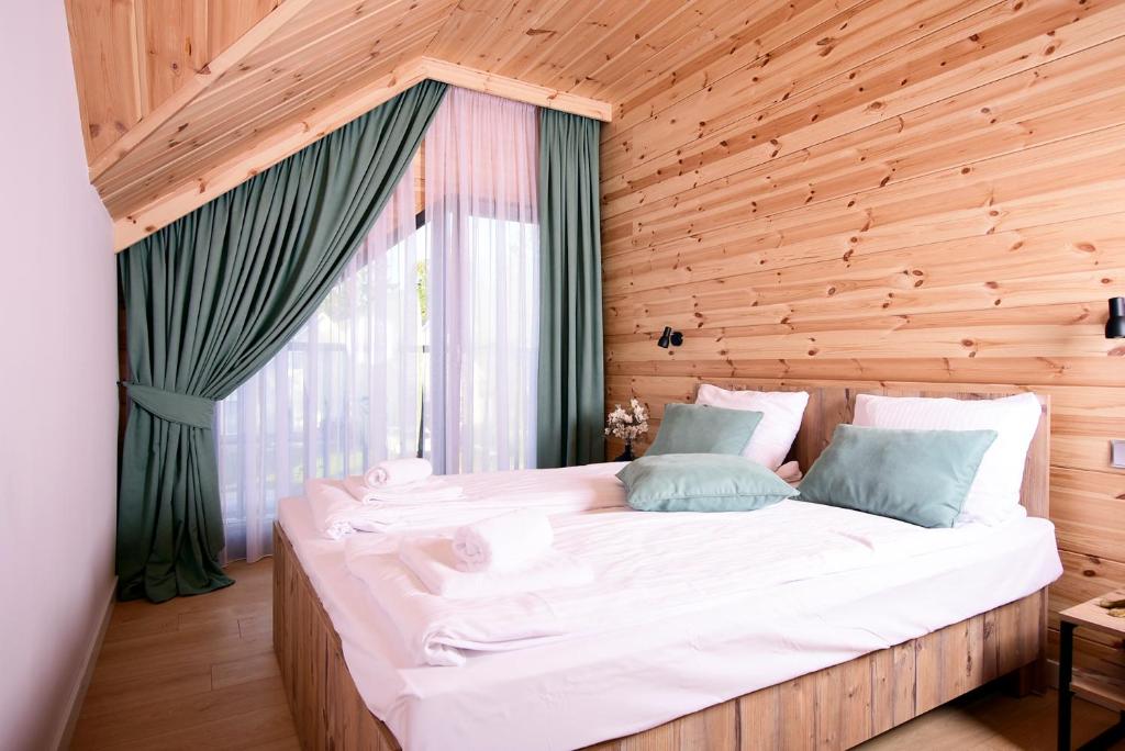 Cette chambre en bois comprend un grand lit et une fenêtre. dans l'établissement Apartamenty Naturapart, à Dziwnów