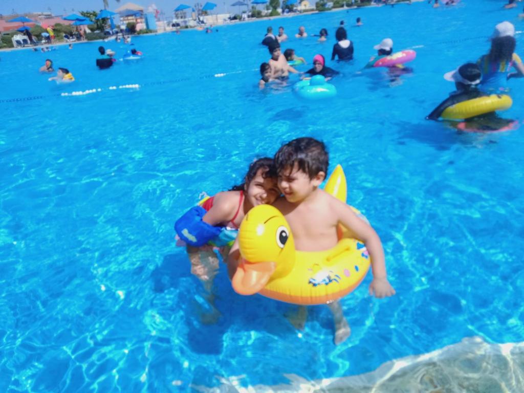 Ein Junge und ein Mädchen im Pool mit einer gelben Gummiente im Wasser. in der Unterkunft Chalets in Porto Sokhna Pyramids in Ain Suchna