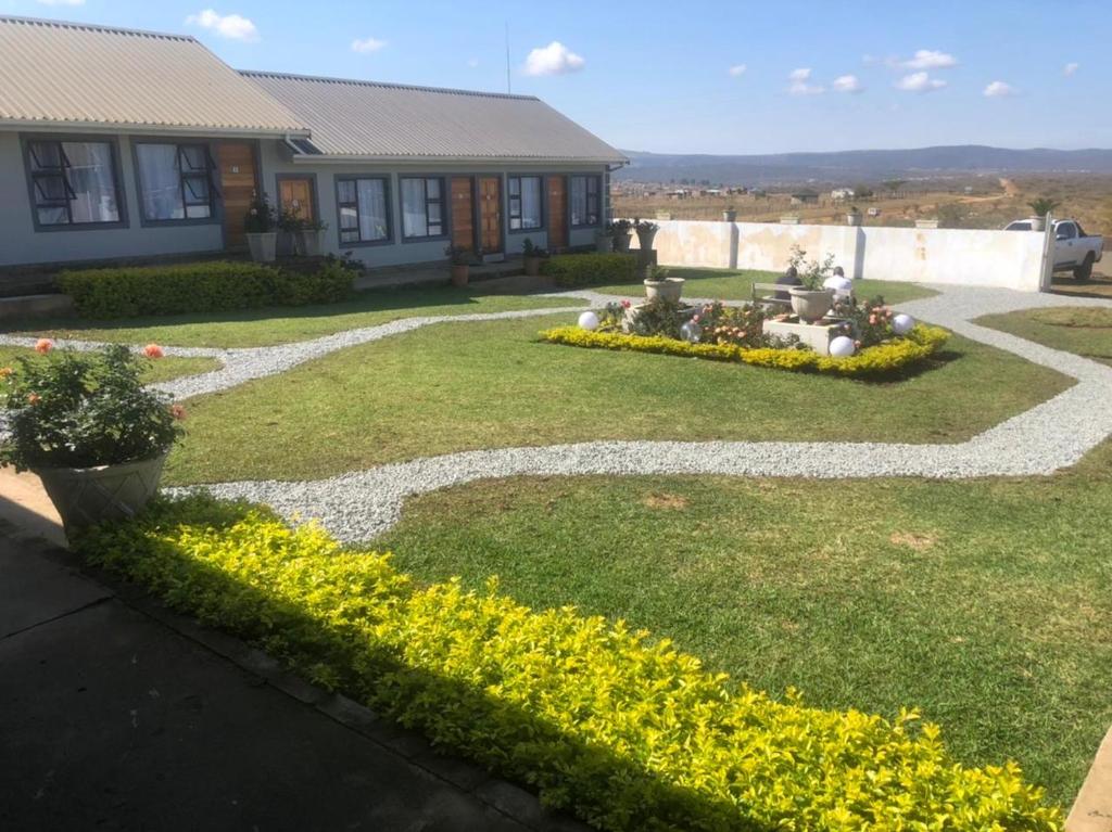 a yard with yellow flowers and a house at Vikamana Guest House in Ulundi