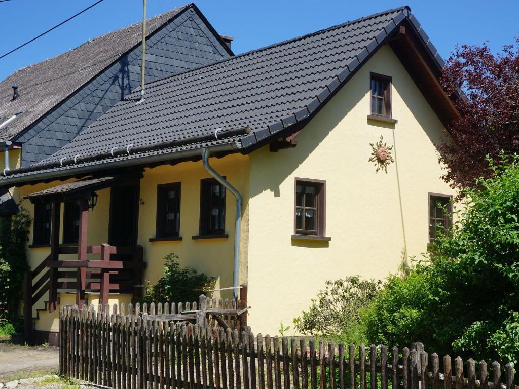 une maison jaune avec un toit noir et une clôture dans l'établissement Ferienhaus am Leiselbach, à Leisel
