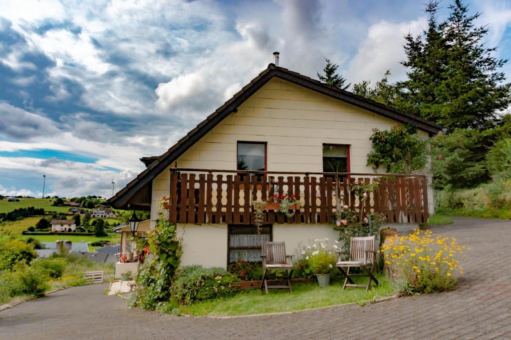 une maison dotée d'un balcon avec des chaises et des fleurs dans l'établissement Ferienhaus ROSENHOF Vulkaneifel, à Ormont