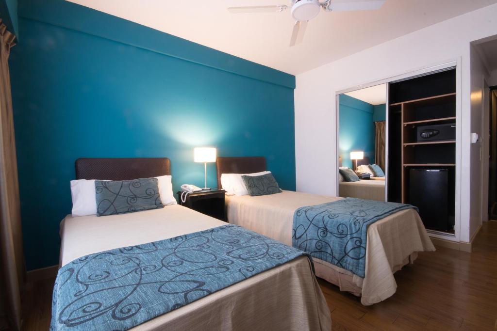 2 camas en una habitación con una pared azul en Gran Hotel Buenos Aires en Buenos Aires