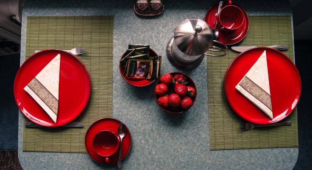 una mesa con platos rojos y un tazón de fresas en Prenzel Apartments - Mai, en Pärnu