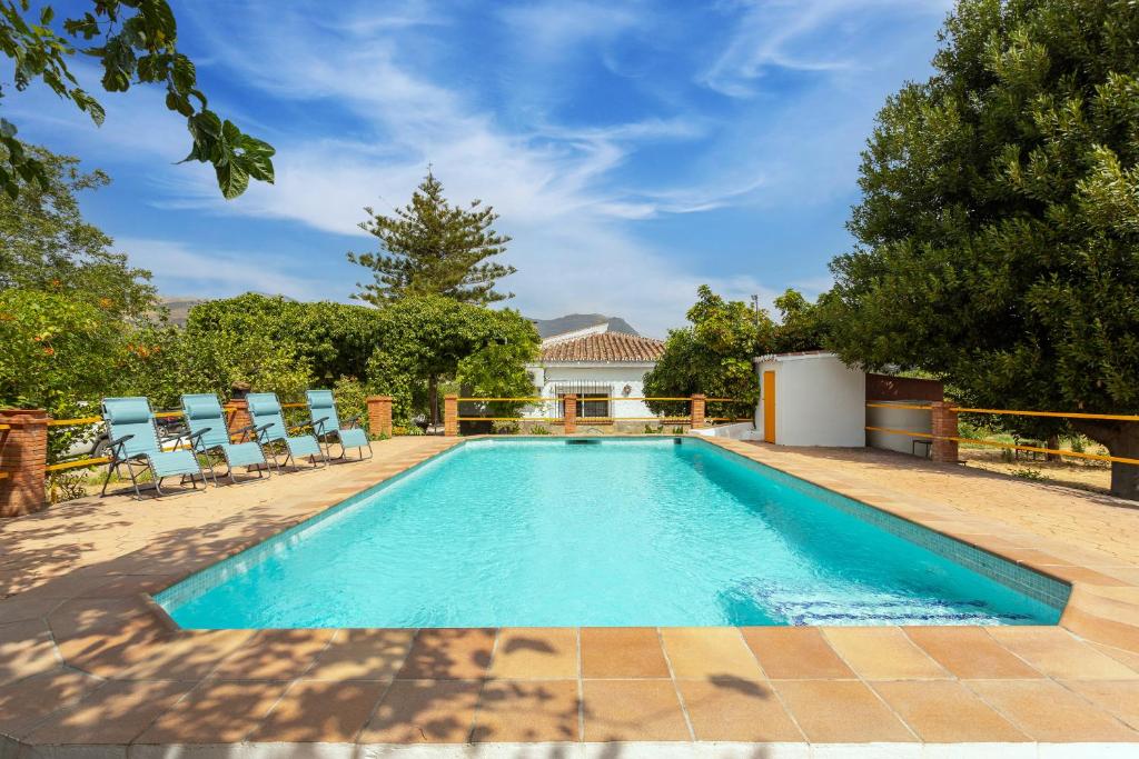 a swimming pool with chairs and a house at Casa rural El Polvillar / Piscina privada in Alora