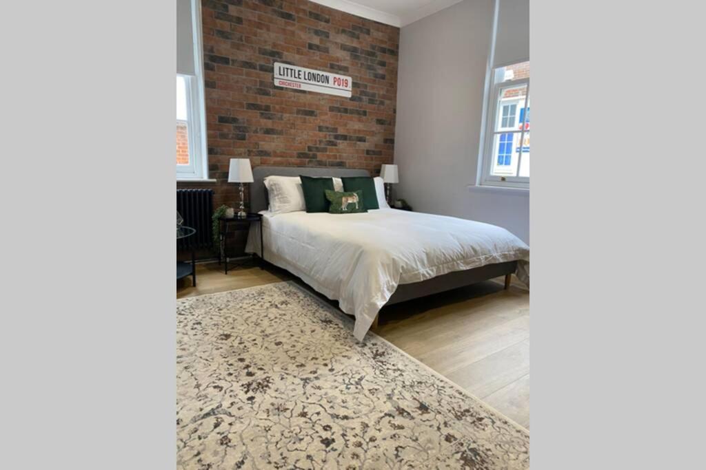 um quarto com uma cama e uma parede de tijolos em City Centre Entire Studio Apartment em Chichester