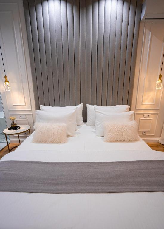 a large bed with white pillows and a gray headboard at Suite Hotel in Kemerovo