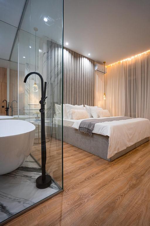 a bedroom with a tub and a bed with a glass wall at Suite Hotel in Kemerovo