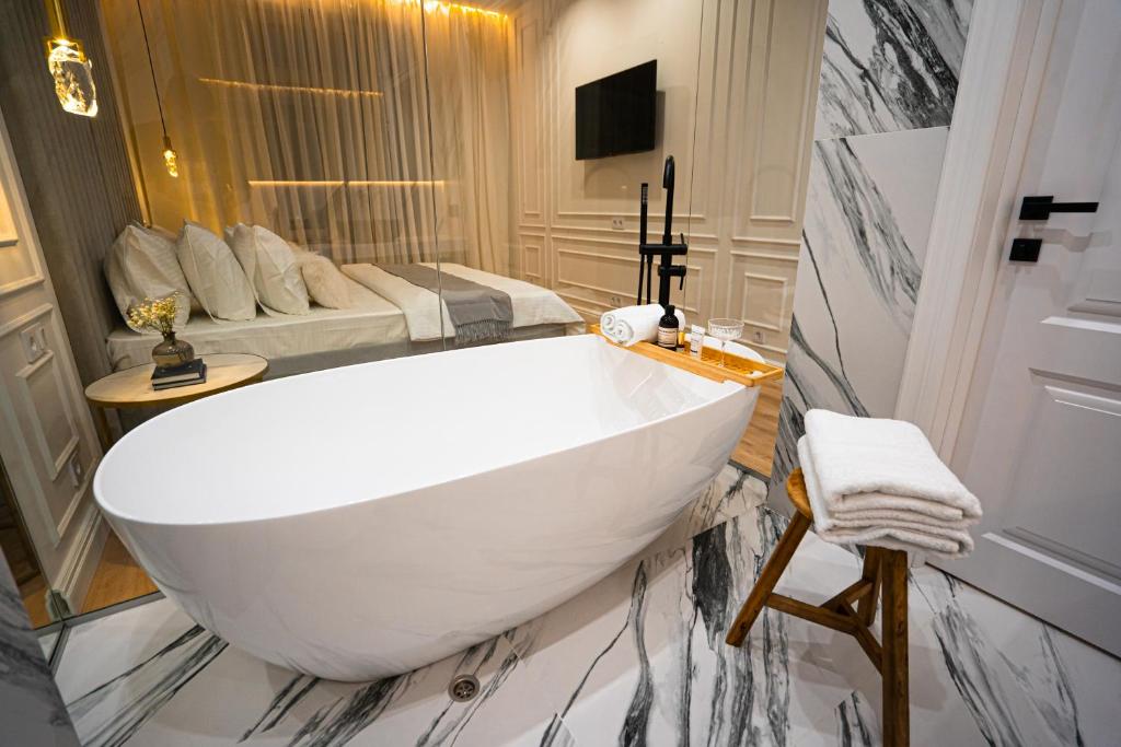a bathroom with a large white sink and a bed at Suite Hotel in Kemerovo