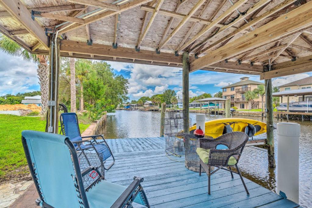 a wooden deck with chairs and a table and a boat at Waterfront Home with Dock, Kayaks, Pool and More! in Crystal River
