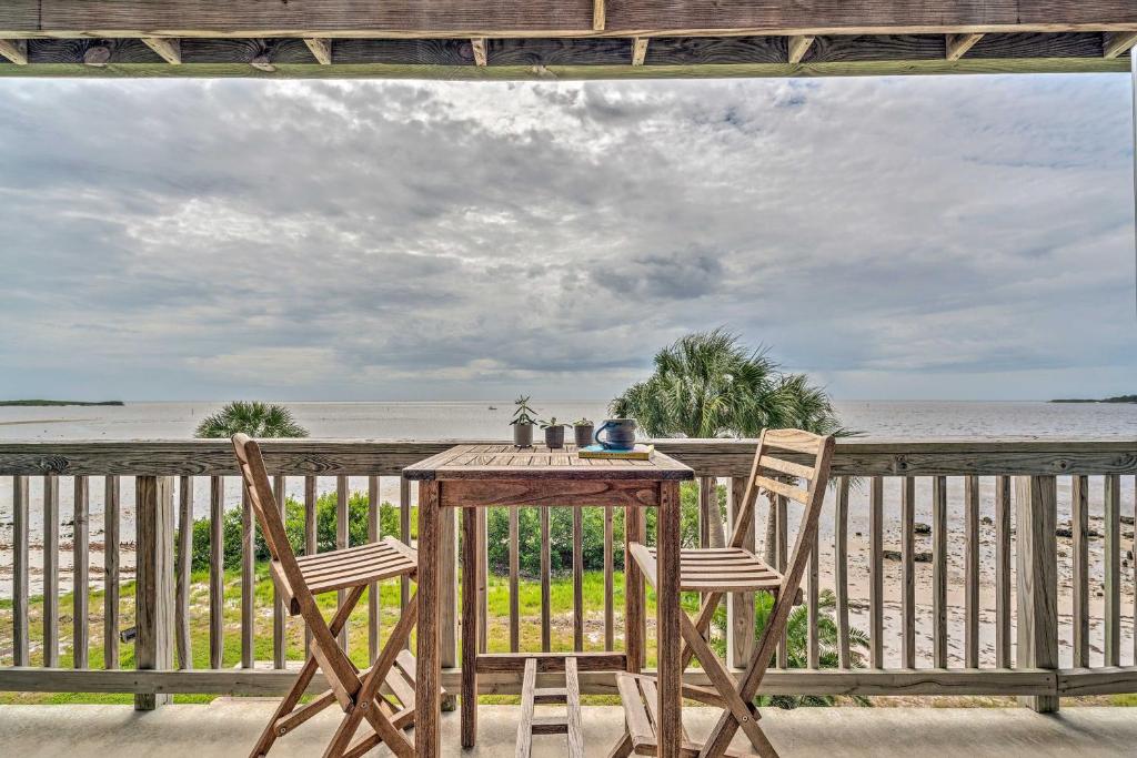 a table and two chairs on a porch with the beach at Charming Cedar Key Condo Direct Beach Access in Cedar Key