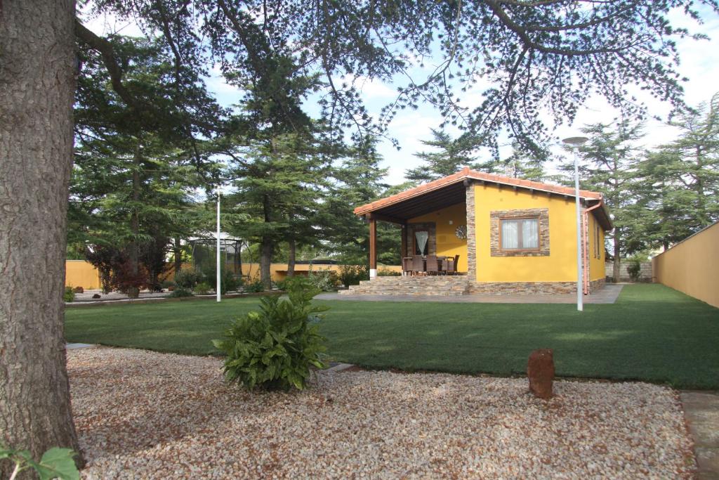 una pequeña casa amarilla con un patio verde en El Rincón de Guica, en Teruel