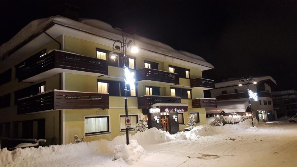 a snow covered building with a street light in front of it at Hotel Cristallo in Madonna di Campiglio