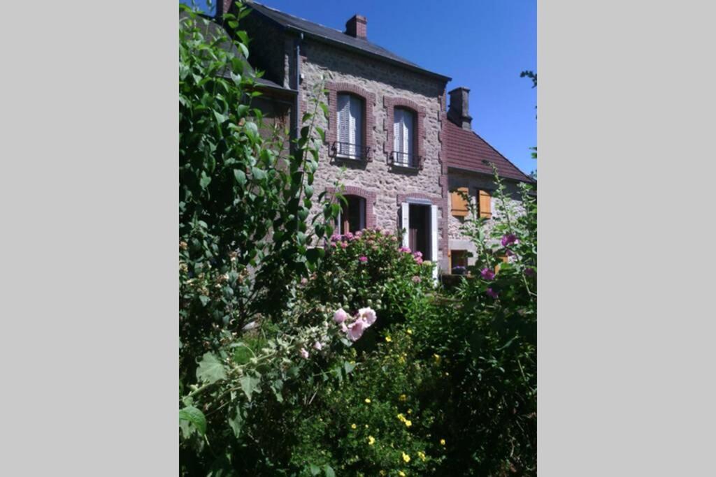 a stone house with flowers in front of it at La maison d'Auguste in Blaudeix