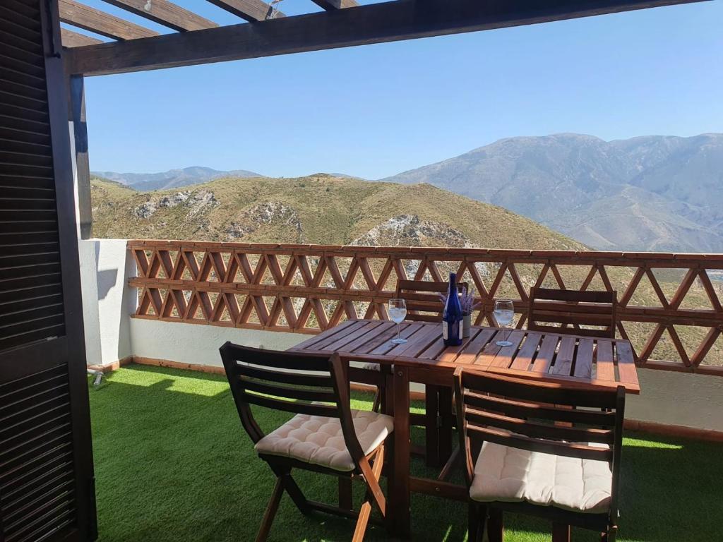 Una mesa y sillas de madera en un balcón con montañas. en tuGuest Carataunas Apartment Alpujarra, en Carataunas