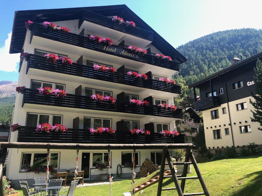 a building with flowers on the balconies of it at Hotel Adonis in Zermatt