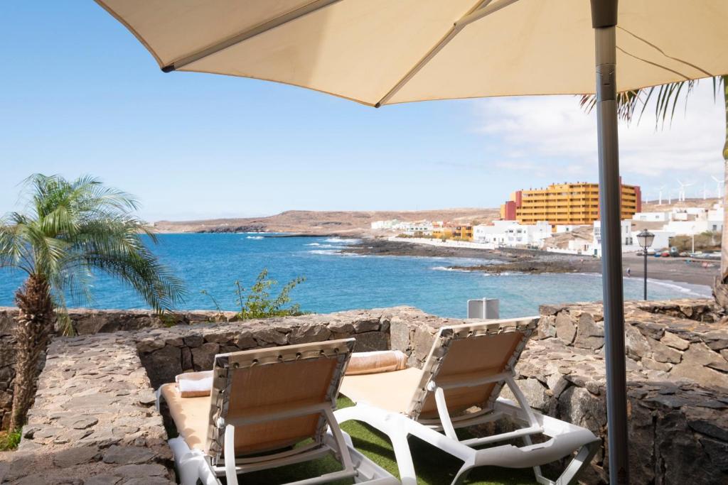 - deux chaises, un parasol et l'océan dans l'établissement Esencias del Mar & Wifi, à Poris de Abona