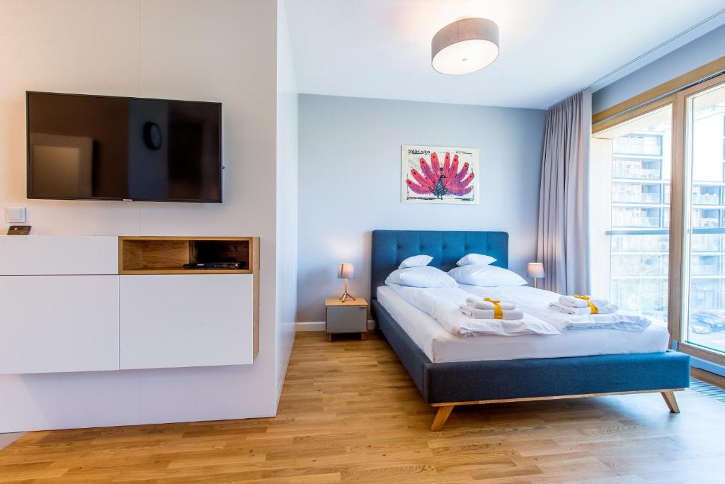 a bedroom with a bed and a tv on a wall at ApartHotel Kolejowa Apartamenty in Warsaw