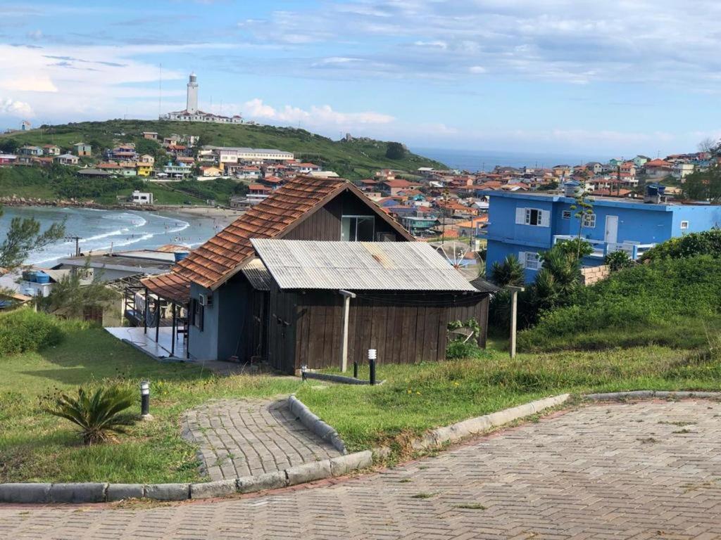 a small house on a hill next to the ocean at Charmosa Casa pertinho do morro do céu in Laguna