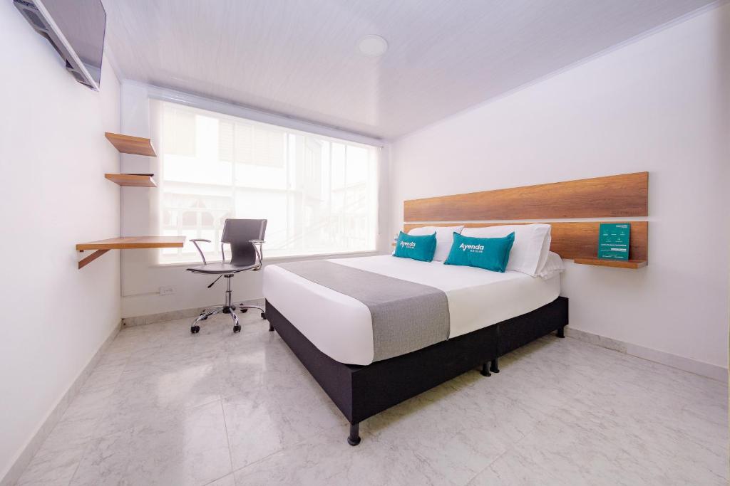 Schlafzimmer mit einem Bett, einem Schreibtisch und einem Fenster in der Unterkunft Casa Mama Hotel in Manizales