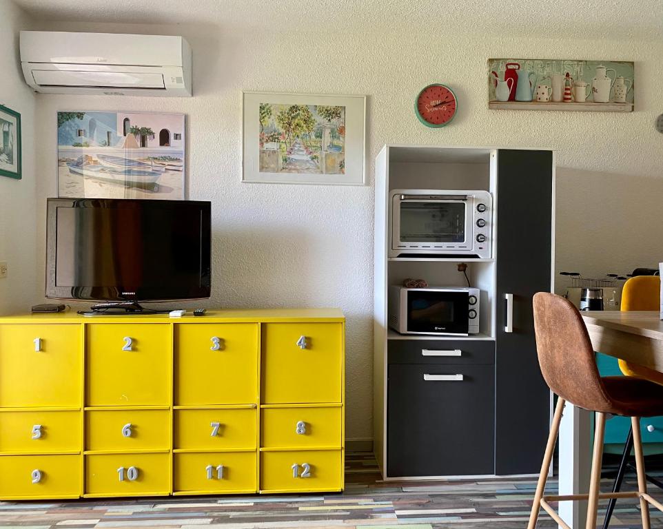 kuchnia z żółtymi szafkami, kuchenką mikrofalową i telewizorem w obiekcie cala di sognu chez Lorenzo w mieście San-Nicolao