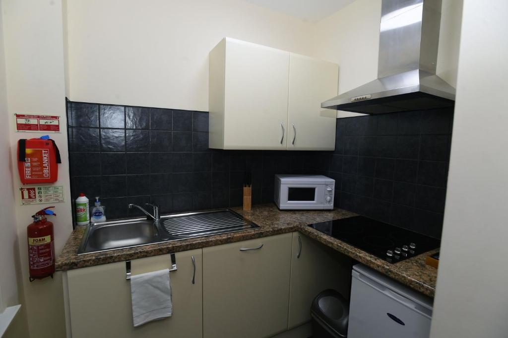 a small kitchen with a sink and a microwave at Ty Dre Town House in Caernarfon
