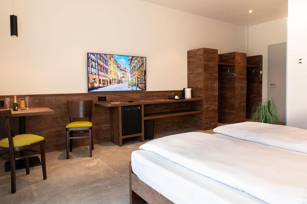 a bedroom with two beds and a desk with a television at Hotel Grüne Elster in Fürth