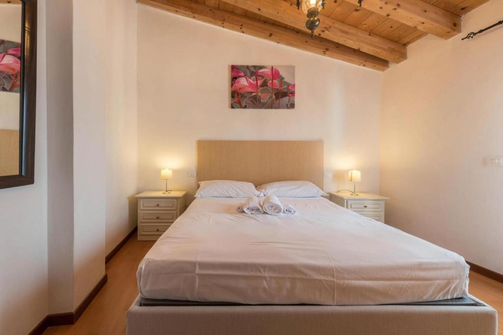 um quarto com uma grande cama branca e 2 candeeiros em il borgo appartamenti con parcheggio em Malcesine