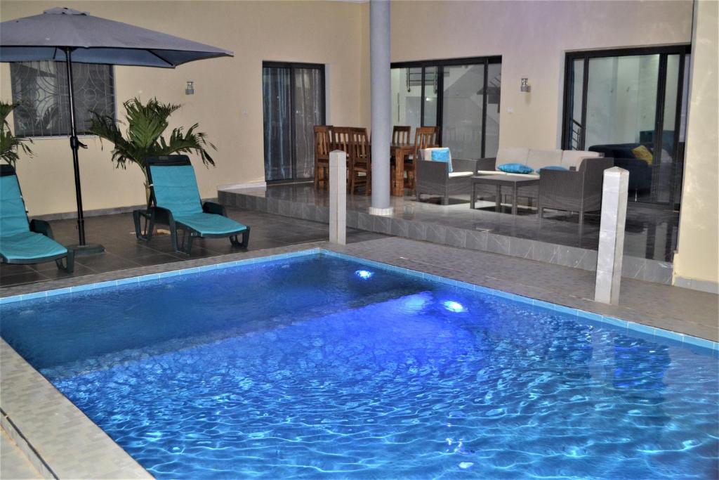 une grande piscine bleue à côté d'un salon dans l'établissement Villa Moderne Spacieuse avec Piscine Privée, 3Ch et 3SdB, à Ngaparou