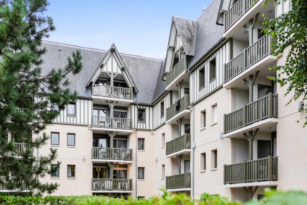 an apartment building with balconies and trees at Residence Pierre & Vacances Les Embruns in Deauville