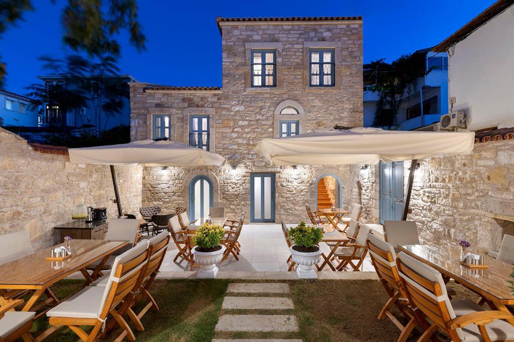 un patio avec des tables et des parasols en face d'un bâtiment dans l'établissement EFLIN HAUS Historical Place & Monument, à Çeşme