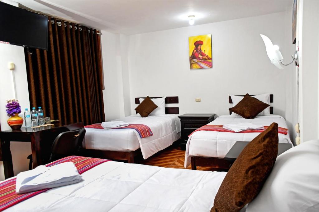 a hotel room with two beds and a desk at Peru Coca B&B Machupicchu in Machu Picchu